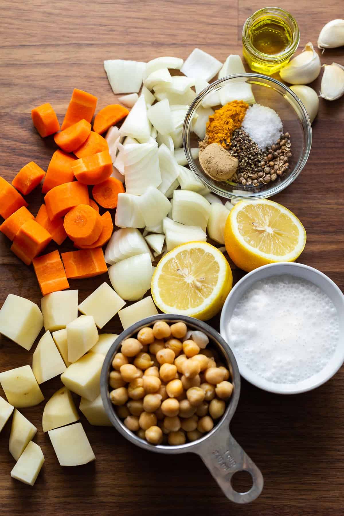 Ingredients for making chickpea turmeric soup: carrots, onion, potatoes, chickpeas, lemon, coconut milk, spices, and garlic.