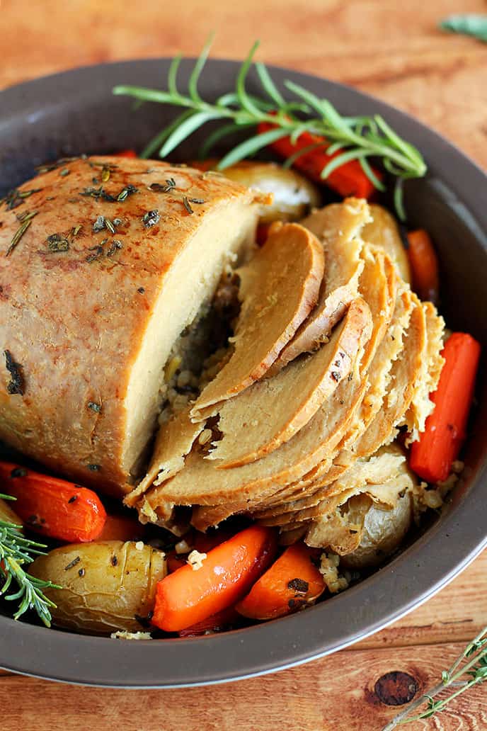 Carved Tofurky roast surrounded by roasted vegetables.