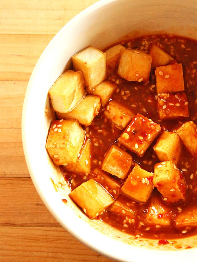 Soaking crispy tofu in peanut sauce to make Teriyaki Peanut Tofu with Stir-Fried Veggies & Brown Rice.