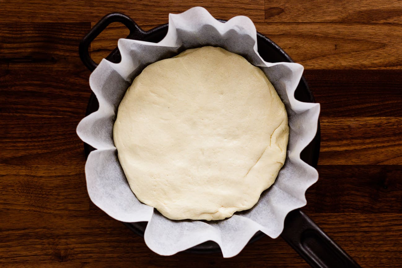 Focaccia dough after being punched down and formed to pan lined with parchment paper.