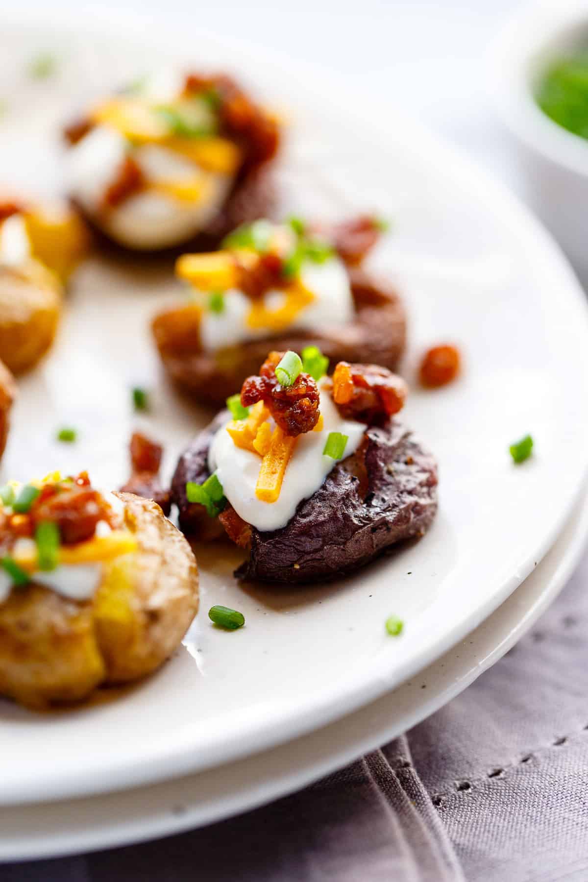 Smashed potatoes loaded with vegan sour cream, vegan cheese, tempeh bacon and chives.
