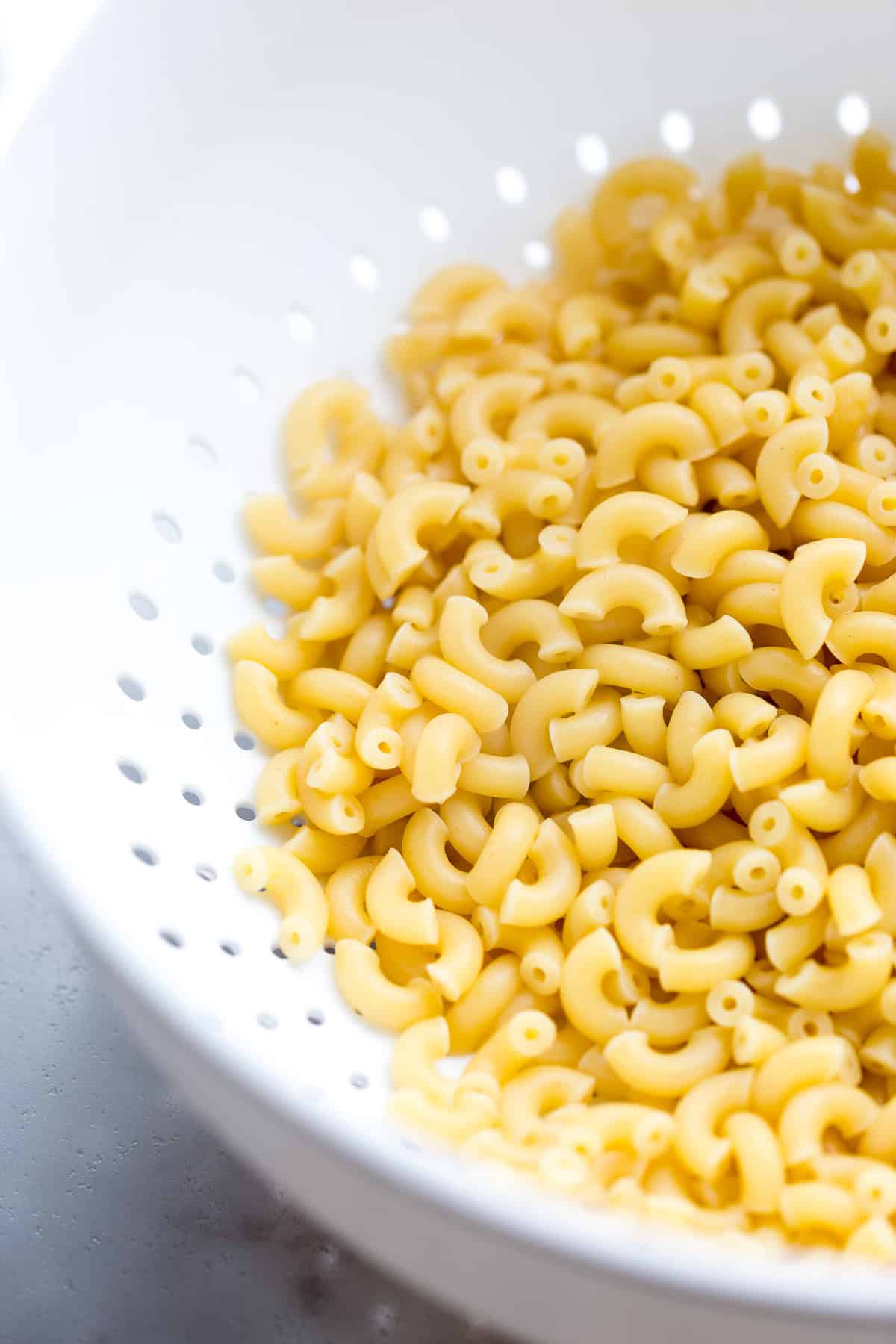 Cooked macaroni noodles in a strainer.