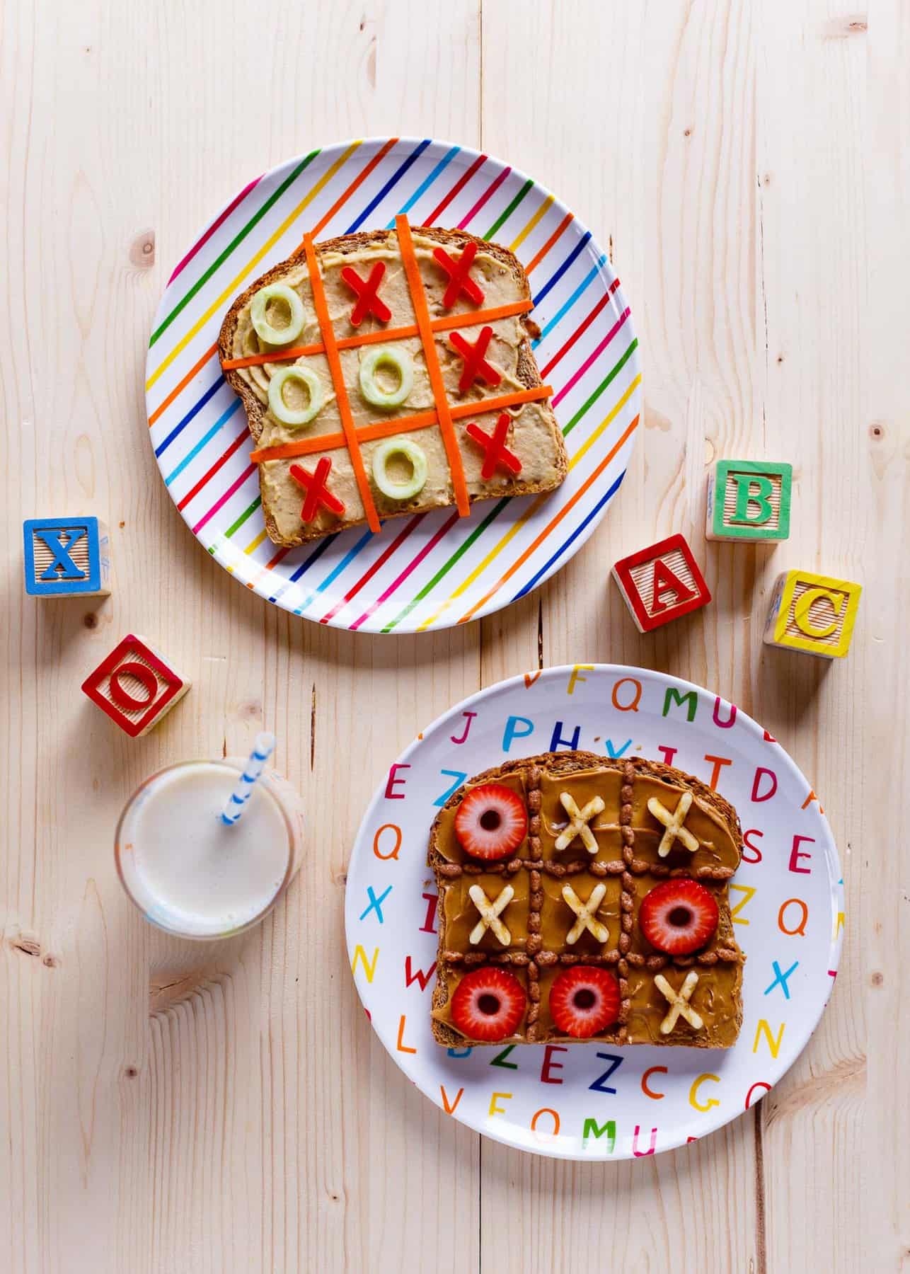 Two pieces of toast decorated as a tic-tac-toe board on colourful patterned plates.